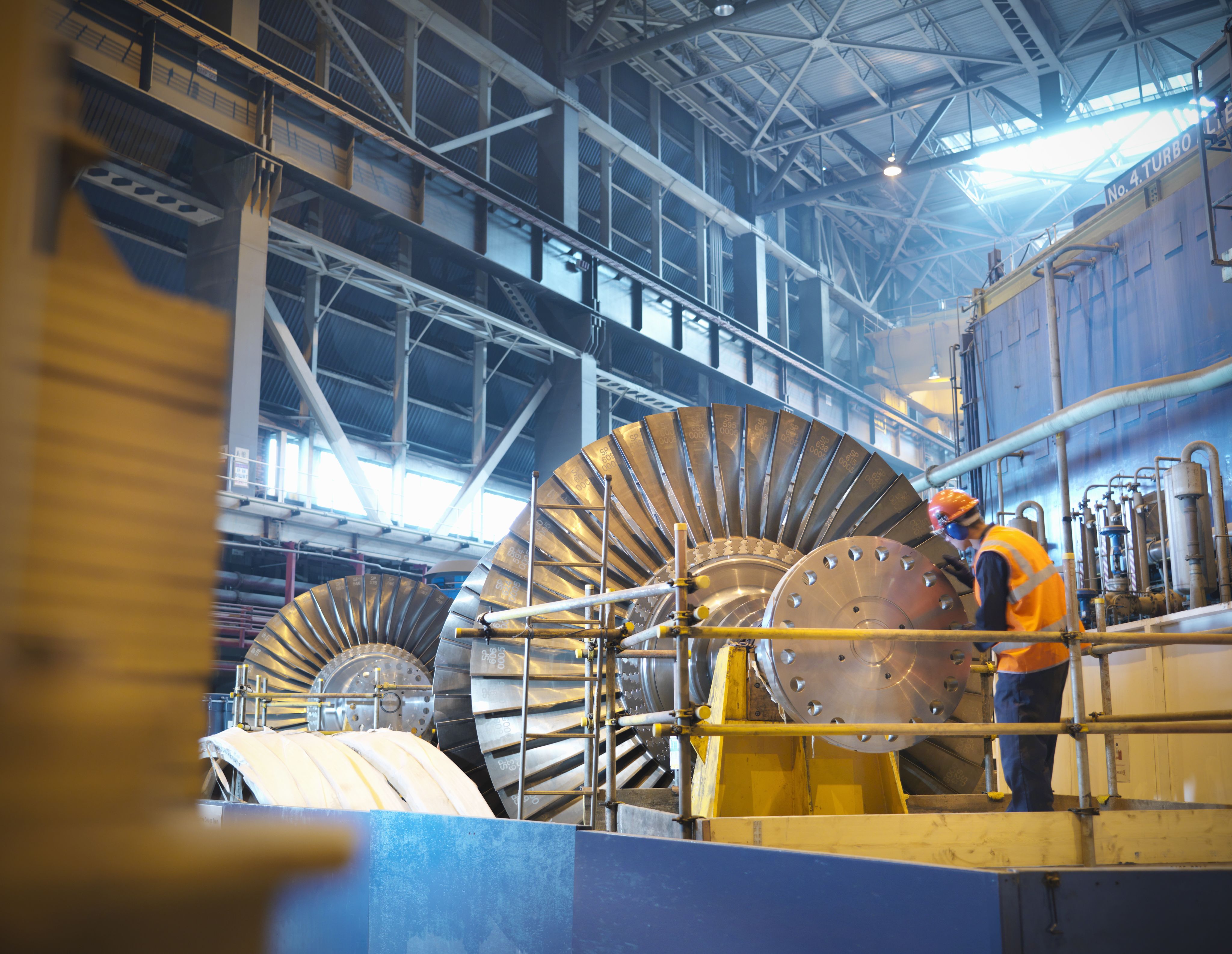 worker maintaining a large electric turbine in a powerplant